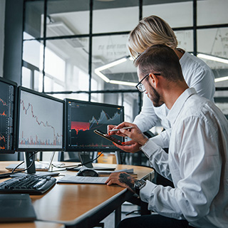 Two stockbrokers in formal clothes works in the office with financial market